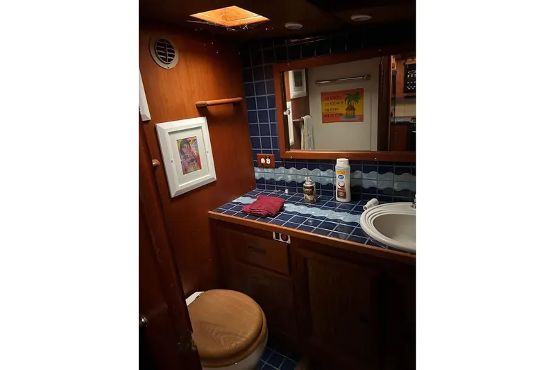 Slide: The Image of 1984 Custom 43 Steady Sailor bathroom with blue tiles, wooden accents, and framed artwork. - 37