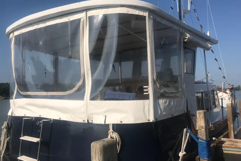 Slide: The Image of Custom 1984 43 Steady Sailor boat docked, featuring enclosed cabin and nautical ropes. - 7