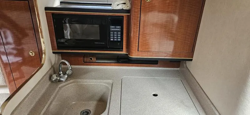 Slide: The Image of 2001 Sea Ray Sundancer 280 galley with sink, microwave, and storage cabinets. - 3