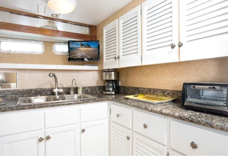 Slide: The Image of 1970 Chris-Craft Commander kitchen with granite countertops, white cabinets, and modern appliances. - 12