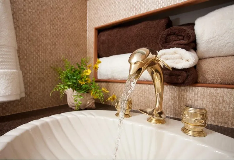 Slide: The Image of Luxurious bathroom sink with gold faucet, plush towels, and decorative flowers. - 18