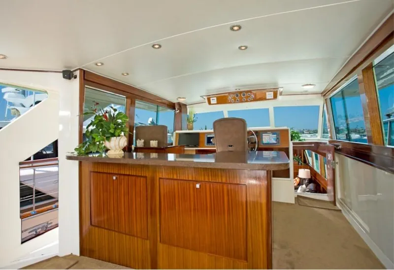 Slide: The Image of 1970 Chris-Craft Commander interior with wood paneling and helm, featuring large windows and plants. - 5