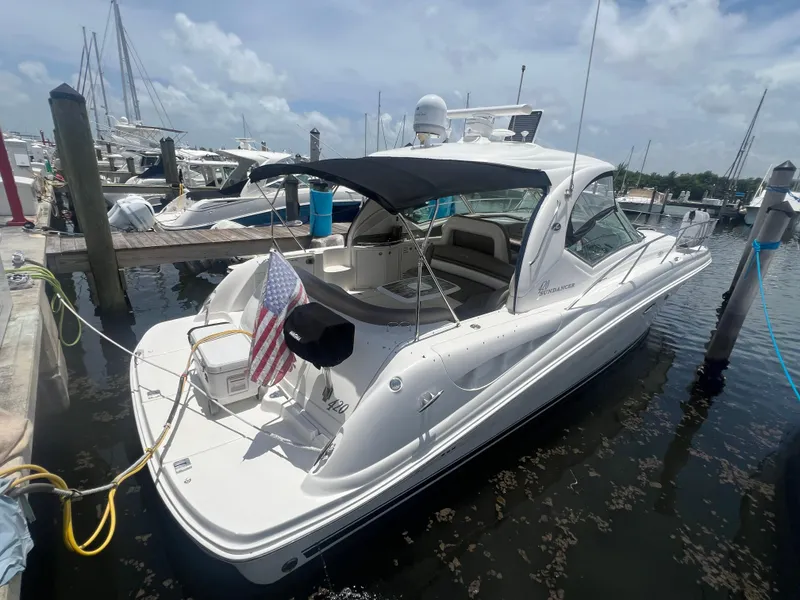The Image of 2005 Sea Ray 420 Sundancer yacht docked at marina, featuring sleek design and American flag. - 0
