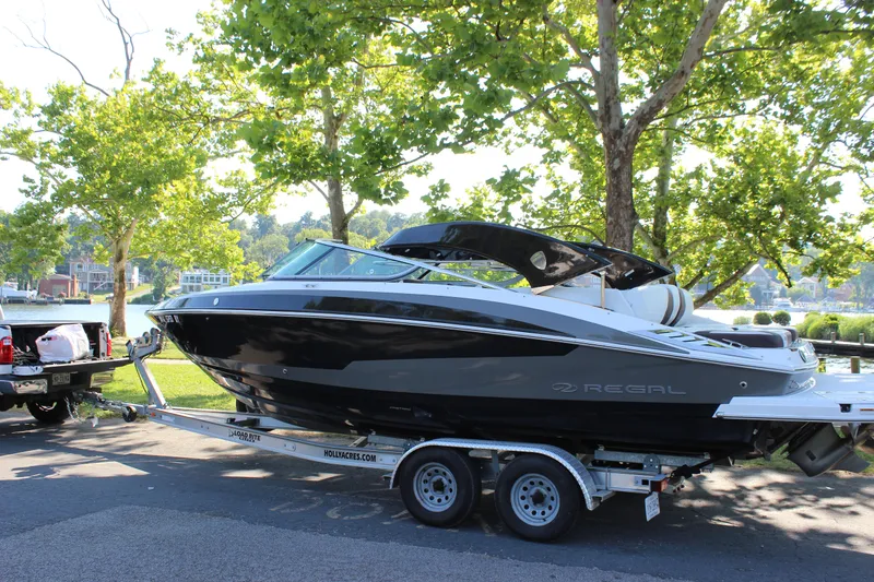 Slide: The Image of 2016 Regal 2500 Bowrider boat on a trailer near a lake. - 3