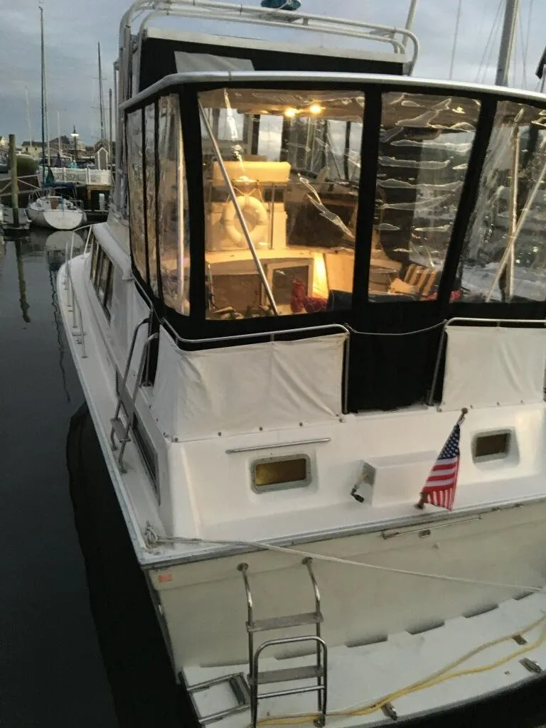 Slide: The Image of 1989 Silverton 40 Aft Cabin yacht docked, featuring a spacious aft deck and American flag. - 1