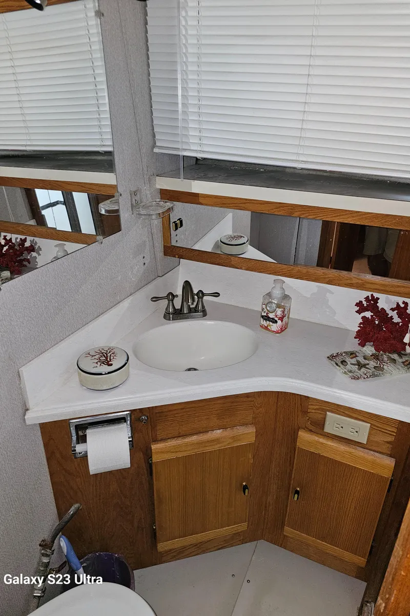 Slide: The Image of 1989 Silverton 40 Aft Cabin bathroom with sink, wooden cabinets, and decorative items. - 14