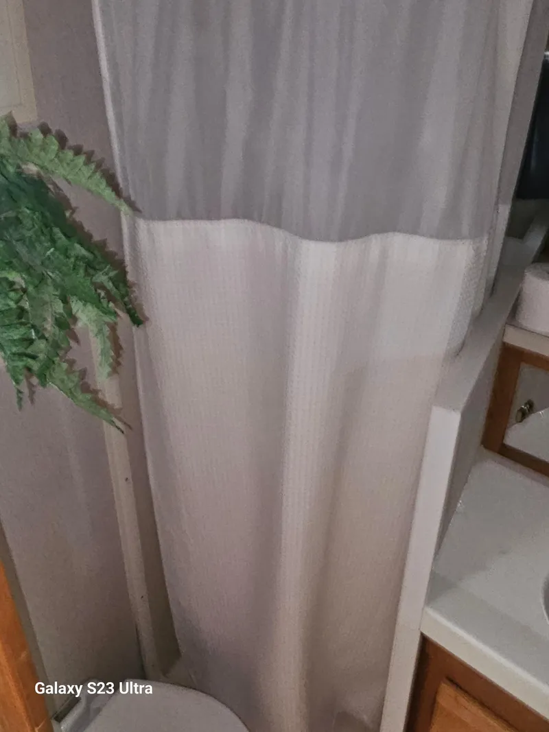 Slide: The Image of 1989 Silverton 40 Aft Cabin bathroom with shower curtain and plant. - 15