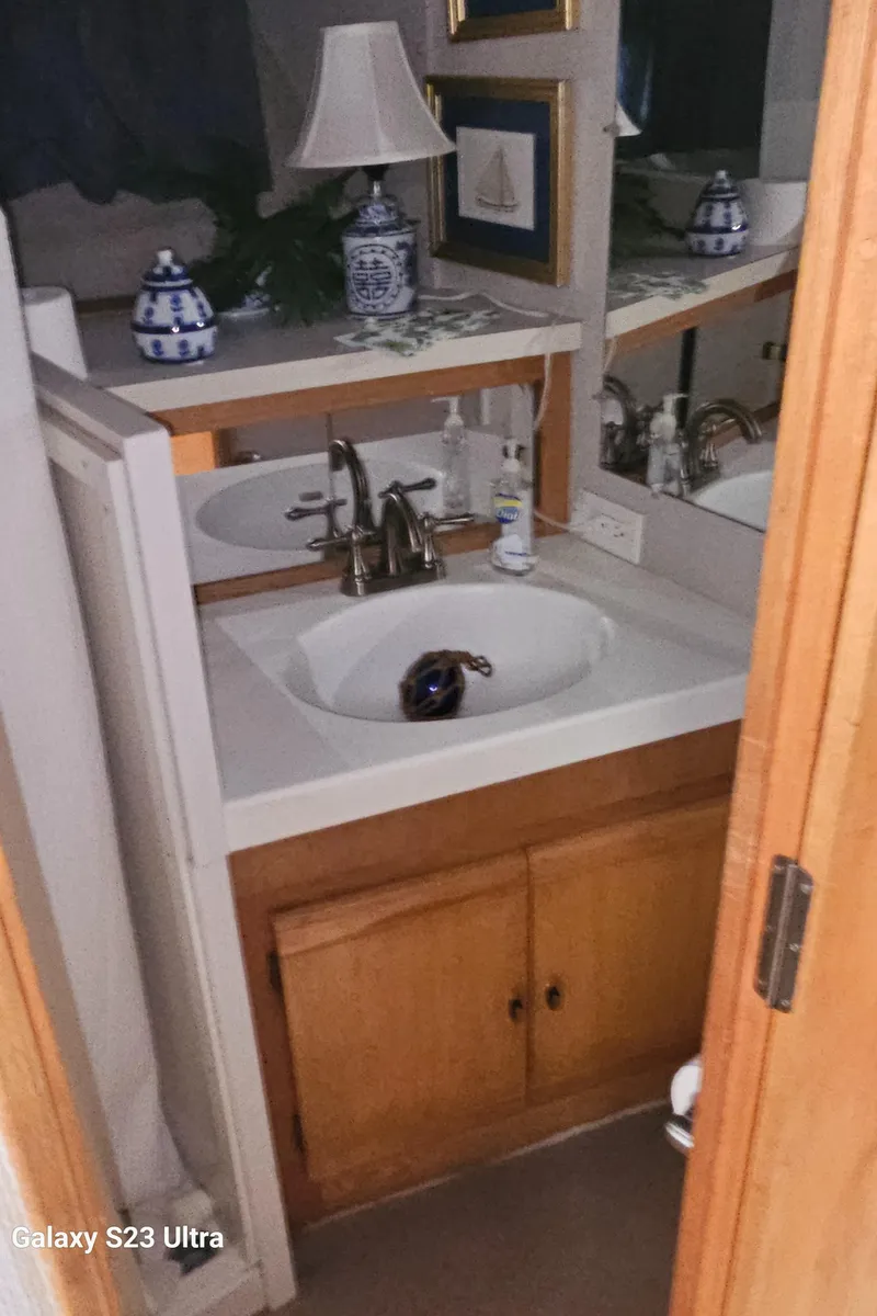 Slide: The Image of 1989 Silverton 40 Aft Cabin bathroom with sink, mirror, and decorative items. - 17