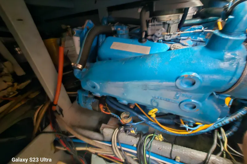 Slide: The Image of Engine compartment of a 1989 Silverton 40 Aft Cabin boat, featuring blue machinery and wiring. - 19