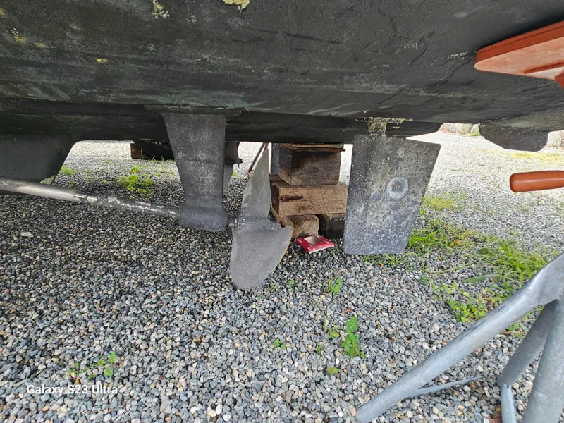 Slide: The Image of 1989 Silverton 40 Aft Cabin boat underside with propeller and rudder on gravel. - 20