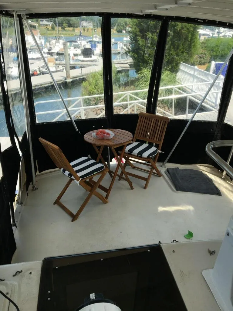 Slide: The Image of 1989 Silverton 40 Aft Cabin yacht interior with wooden chairs and table, marina view. - 21