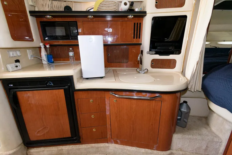 Slide: The Image of 1999 Sea Ray 340 Sundancer galley with microwave, fridge, sink, and storage cabinets. - 10
