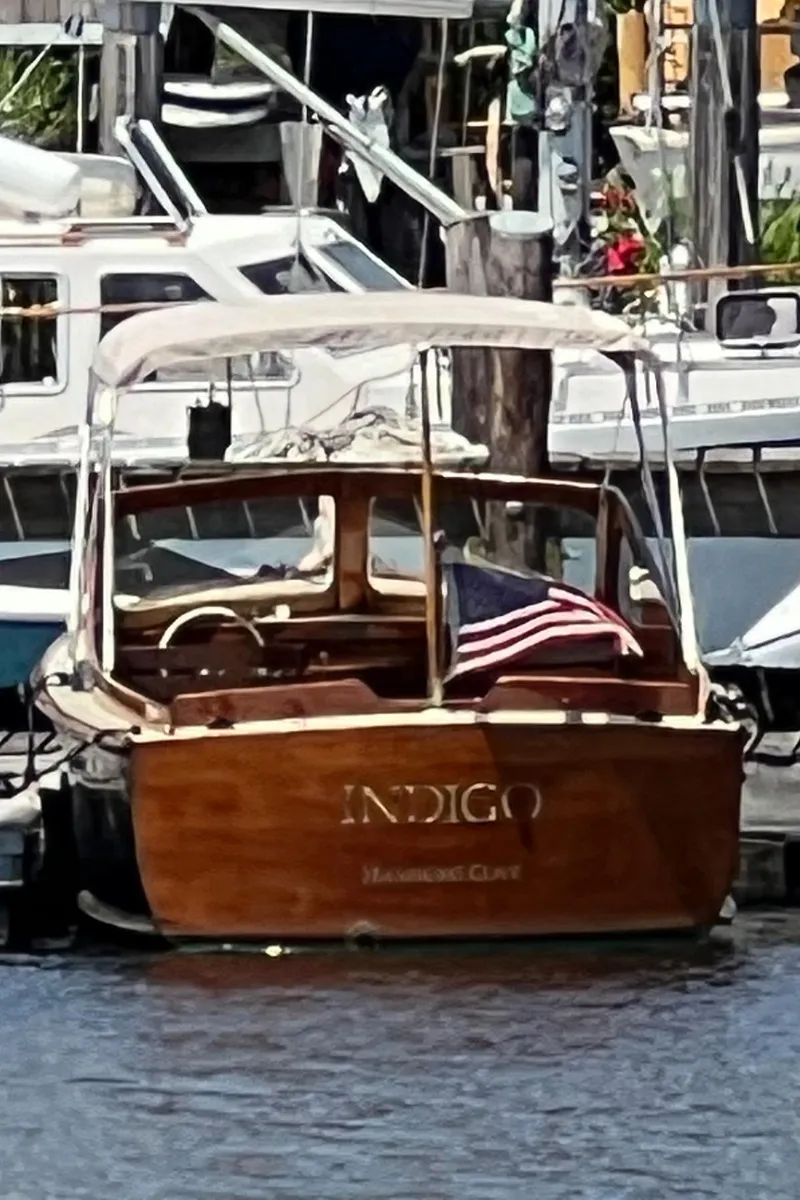 Slide: The Image of Vintage 1952 Palmer Scott 22 boat "Indigo" docked, featuring classic wooden design and American flag. - 16