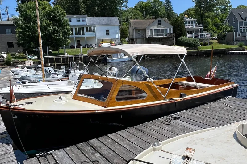 Slide: The Image of 1952 Custom Palmer Scott 22 boat docked by a scenic waterfront with houses in the background. - 3