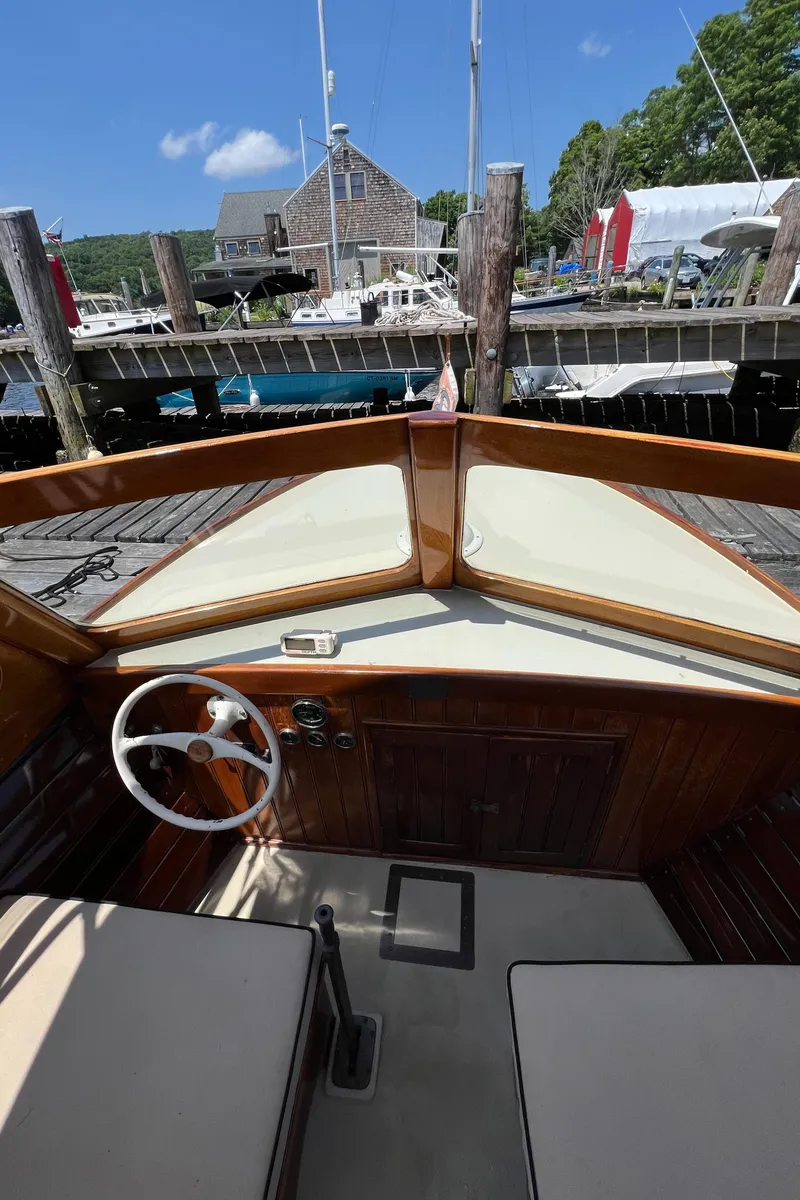 Slide: The Image of 1952 Custom Palmer Scott 22 boat interior with wooden dashboard and steering wheel at a dock. - 8
