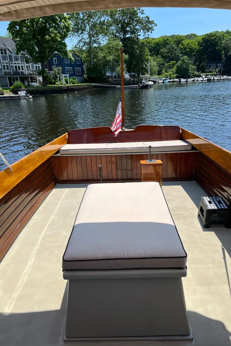 Slide: The Image of 1952 Custom Palmer Scott 22 boat with cushioned seating, docked by a scenic waterfront. - 9