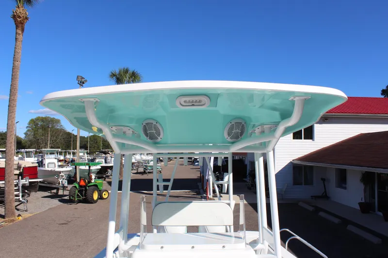 Slide: The Image of 2024 Clearwater 2300 WI boat with T-top and speakers in marina. - 14