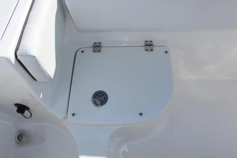 Slide: The Image of 2024 Clearwater 2300 WI boat storage compartment with white cushioned seating. - 24
