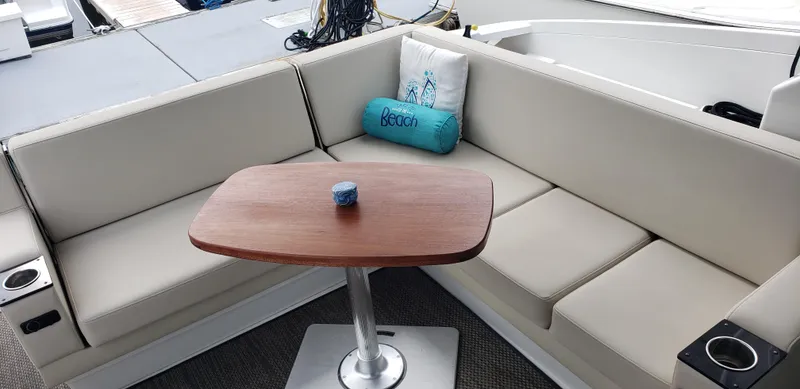 Slide: The Image of Interior seating area of a 2016 Monterey 360 Sport Coupe boat with a wooden table. - 9