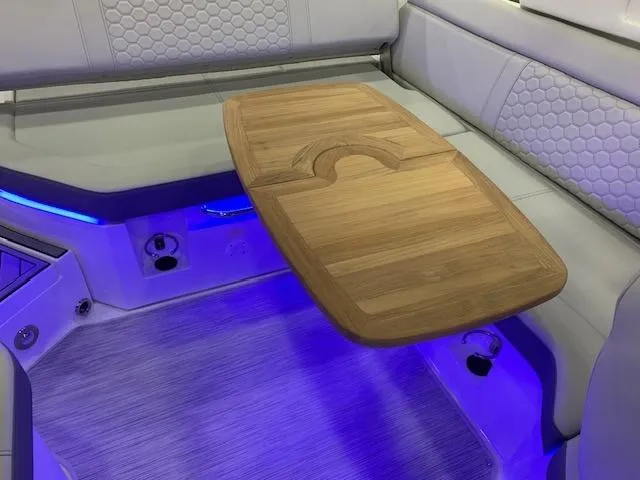 Slide: The Image of 2024 Sea Ray SDX 250 boat interior with wooden table and blue LED lighting. - 12