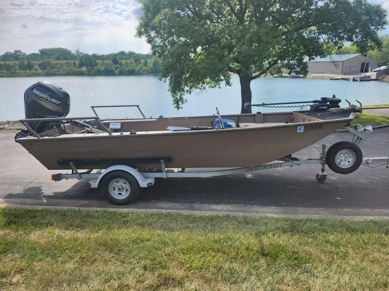 Slide: The Image of 2015 Smoker Craft Sportsman Pro 1866 boat on trailer by a lake. - 10