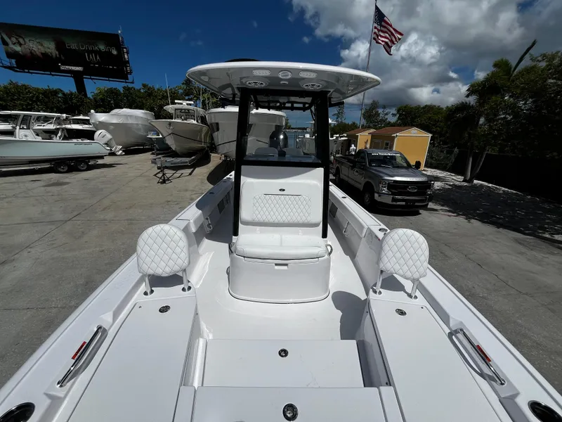 Slide: The Image of 2024 Sportsman Masters 247 Bay Boat, front deck view, docked with American flag in background. - 23