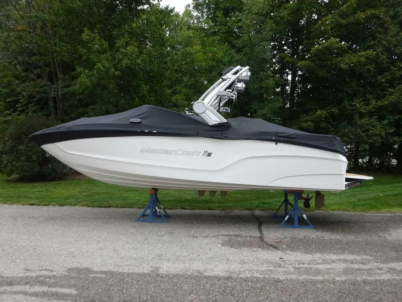 Slide: The Image of 2022 MasterCraft XT23 boat with cover on stands, parked on a paved road. - 5