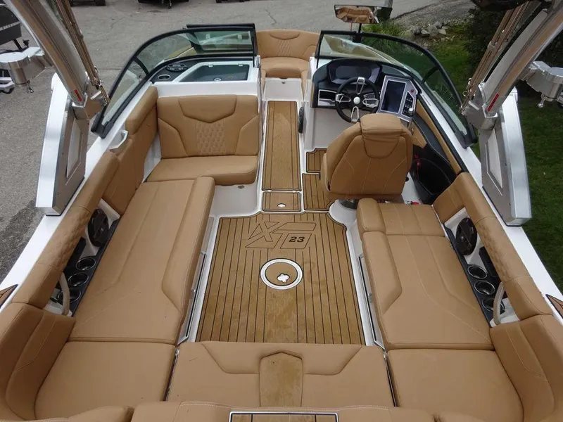 Slide: The Image of 2022 MasterCraft XT23 boat interior with tan seating and modern dashboard. - 7