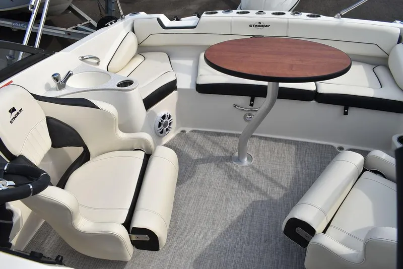 Slide: The Image of 2024 Stingray 201DC boat interior with white leather seats and a round wooden table. - 22