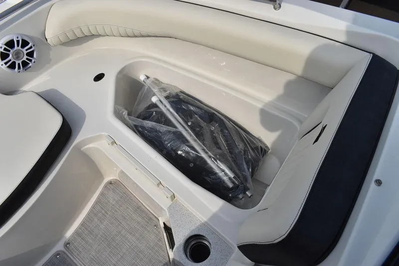Slide: The Image of 2024 Stingray 201DC boat interior storage compartment with cushioned seating and speaker. - 45