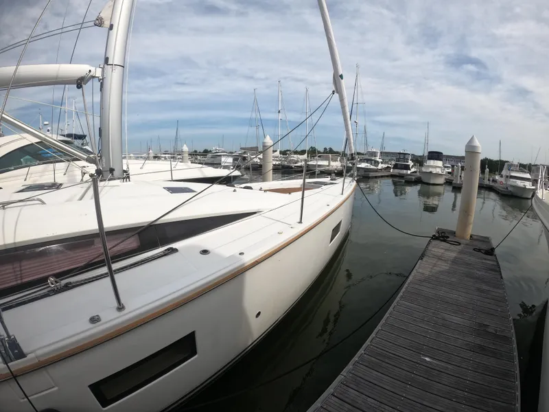 Slide: The Image of 2017 Jeanneau 54 sailboat docked at a marina with other boats. - 12