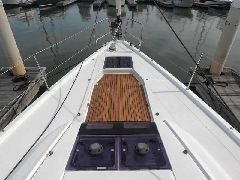 Slide: The Image of 2017 Jeanneau 54 sailboat deck with teak wood and hatches in marina. - 17