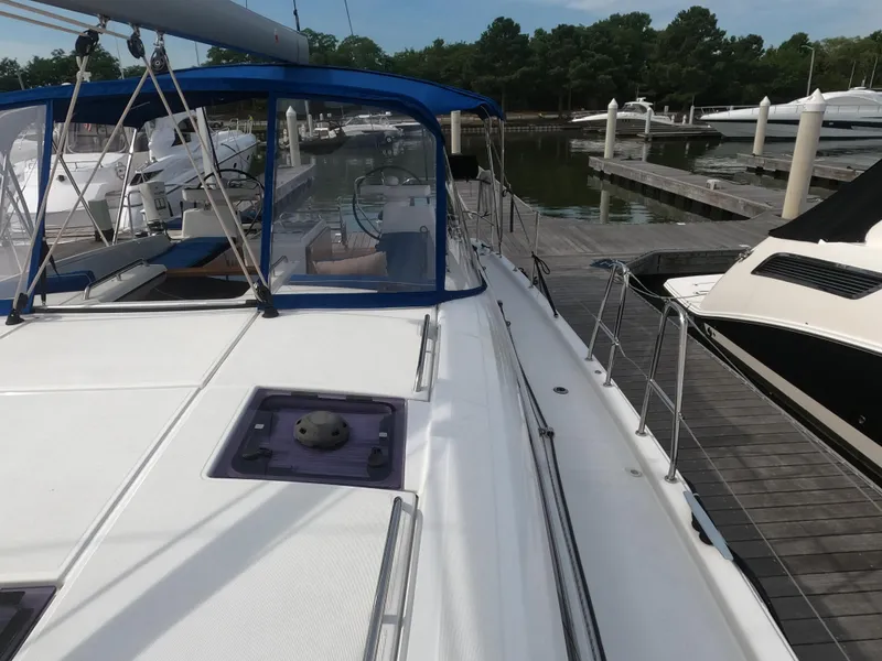 Slide: The Image of 2017 Jeanneau 54 sailboat docked at a marina, featuring a spacious deck and blue canopy. - 18