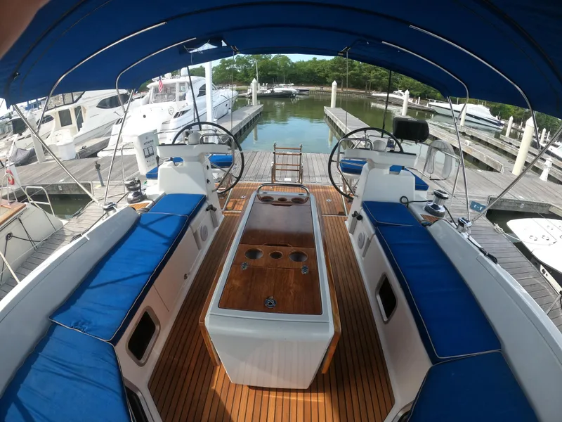 Slide: The Image of 2017 Jeanneau 54 sailboat cockpit with blue cushions and wooden table at marina. - 20