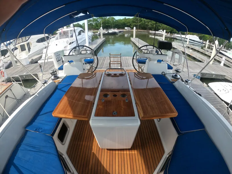 Slide: The Image of 2017 Jeanneau 54 sailboat cockpit with blue canopy and wooden table. - 21