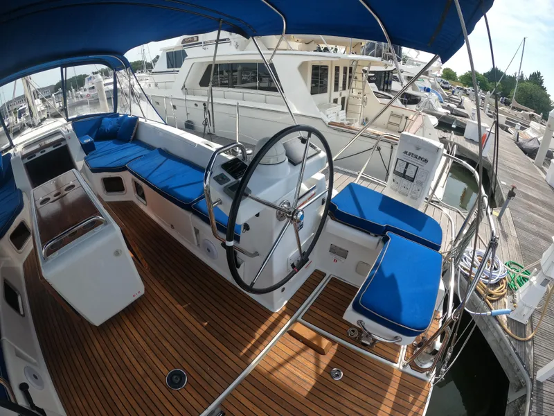 Slide: The Image of Cockpit of 2017 Jeanneau 54 sailboat with blue cushions and wooden deck. - 23