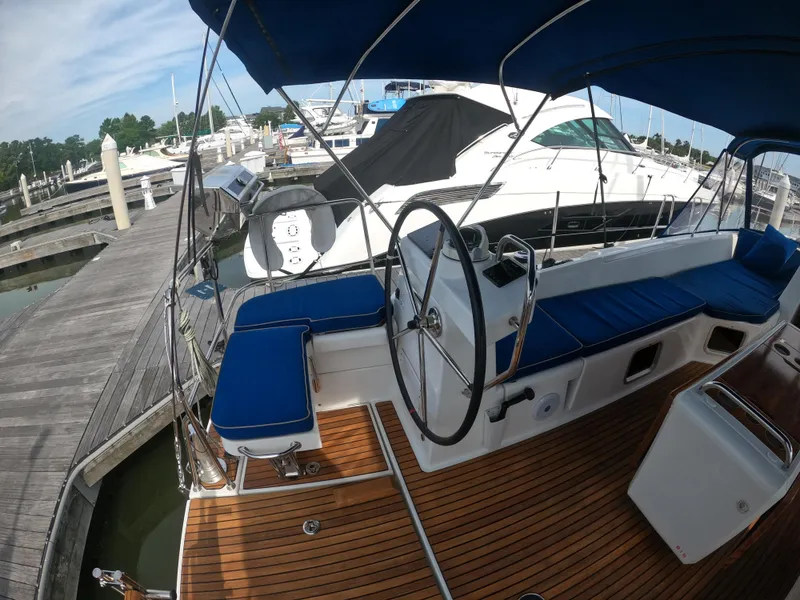 Slide: The Image of 2017 Jeanneau 54 sailboat cockpit with blue cushions and wooden deck at marina. - 27
