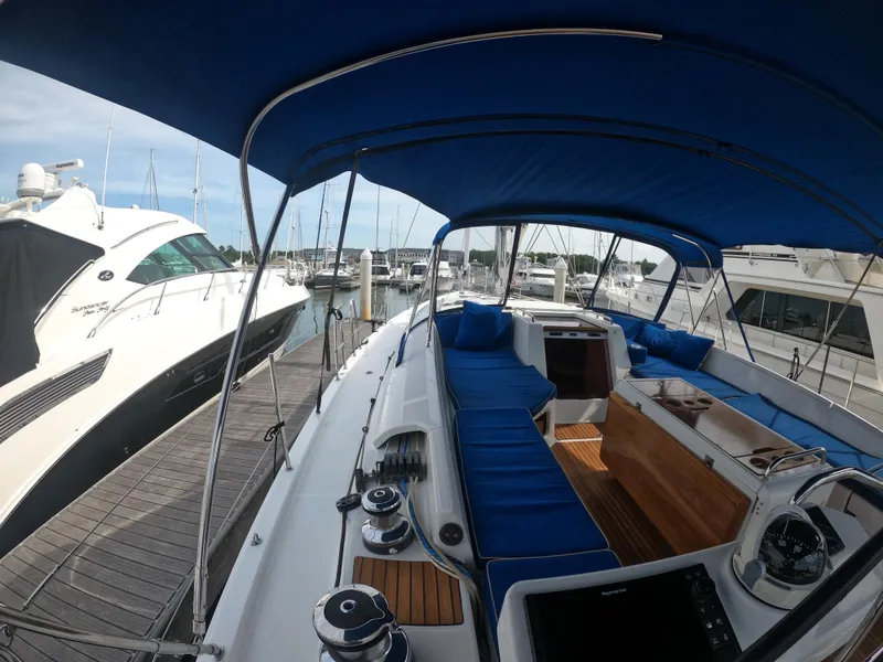 Slide: The Image of 2017 Jeanneau 54 sailboat with blue canopy and cushions docked at marina. - 32