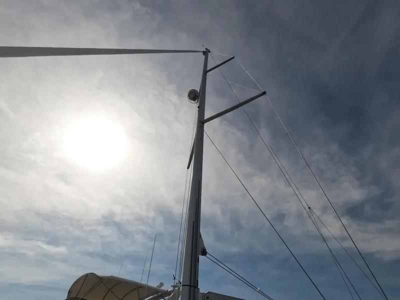 Slide: The Image of Mast of 2017 Jeanneau 54 sailboat against a bright sun and cloudy sky. - 6