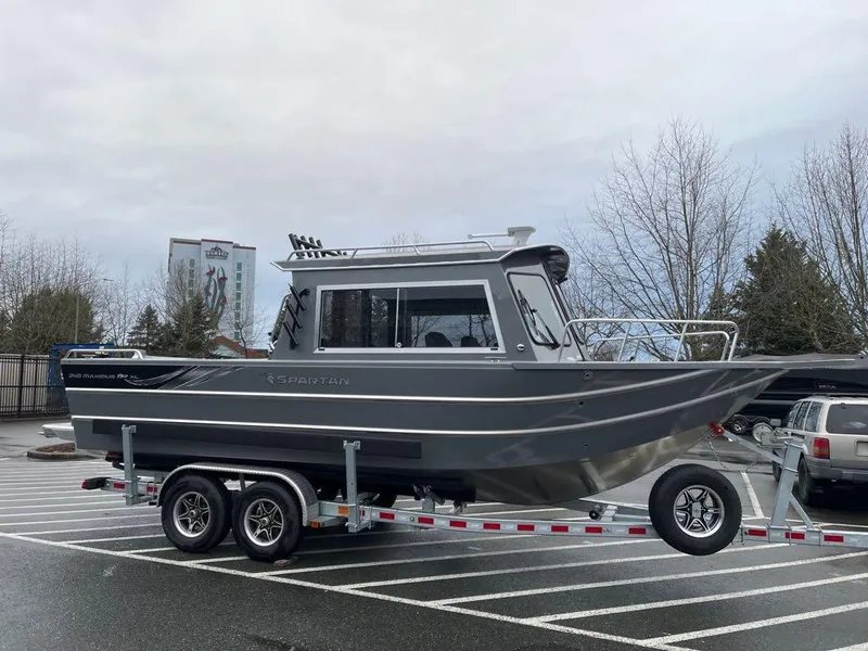 The Image of 2024 Spartan Maximus 240 boat on a trailer in a parking lot. - 0