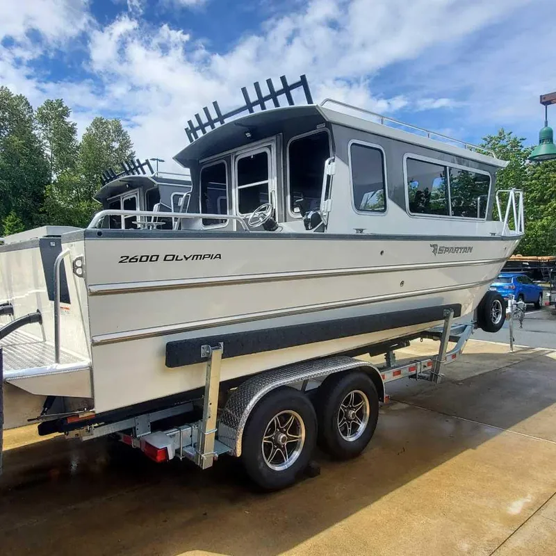 The Image of 2024 Spartan 2600 Olympia boat on a trailer under a blue sky. - 0