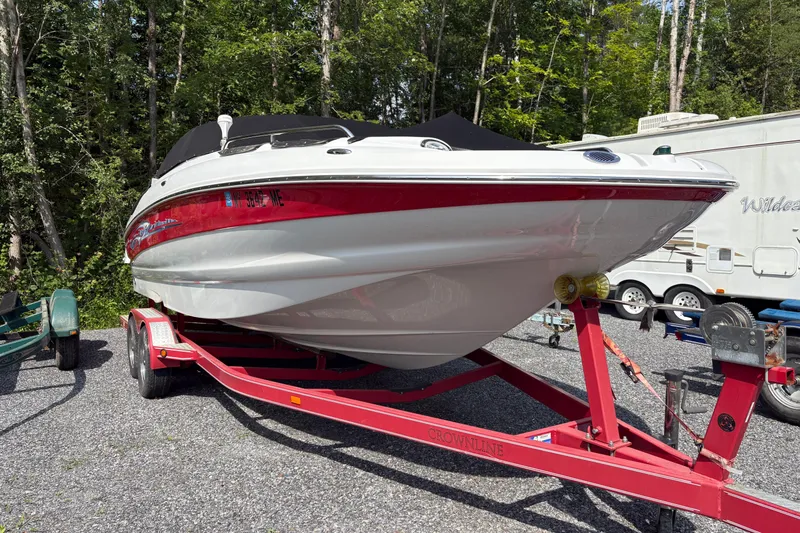 The Image of 2007 Crownline 240 EX boat on red trailer, parked outdoors near trees and RV. - 0