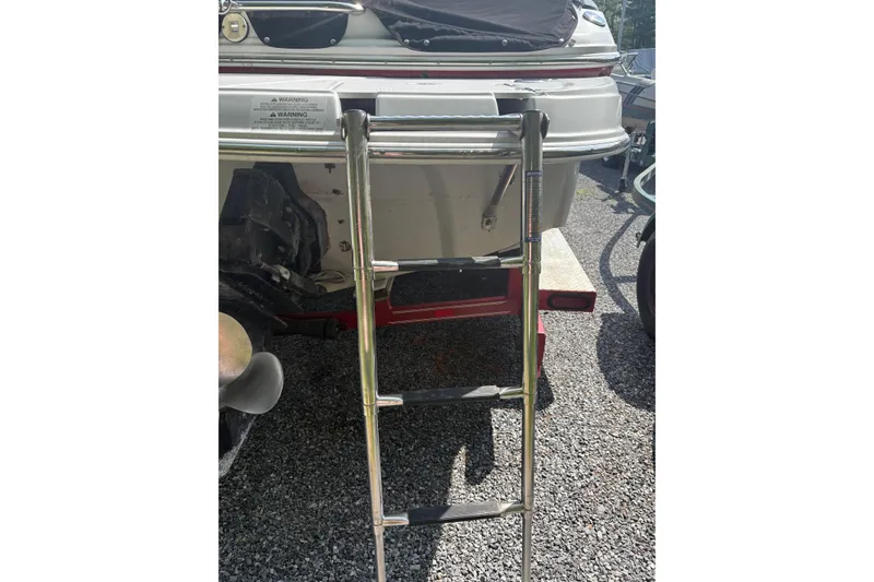 Slide: The Image of 2007 Crownline 240 EX boat with extended swim ladder on gravel surface. - 37