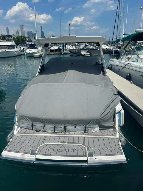 Slide: The Image of 2022 Cobalt A29 boat docked in a marina, covered with a gray tarp. - 3