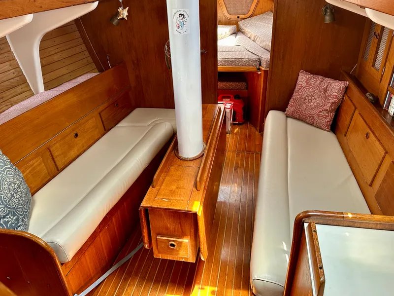 Slide: The Image of Interior of 1980 Alden 44 sailboat with wooden furnishings and white cushions. - 9