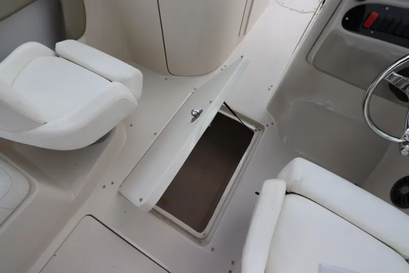 Slide: The Image of 2007 Sea Ray 240 Sundeck interior with open storage compartment and white seating. - 20