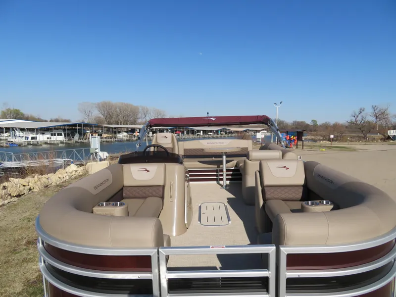 Slide: The Image of 2024 Bennington 22SXSB pontoon boat with beige seating and red accents docked at a marina. - 10
