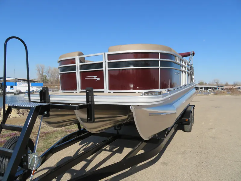 Slide: The Image of 2024 Bennington 22SXSB pontoon boat on a trailer under a clear blue sky. - 2