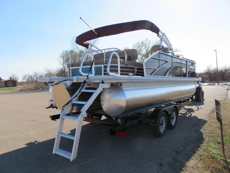Slide: The Image of 2024 Bennington 22SXSB pontoon boat on a trailer, rear view with ladder and canopy. - 5