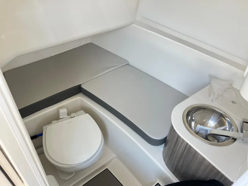 Slide: The Image of 2025 Sea Ray SDX 270 boat interior bathroom with toilet, sink, and cushioned seating. - 9